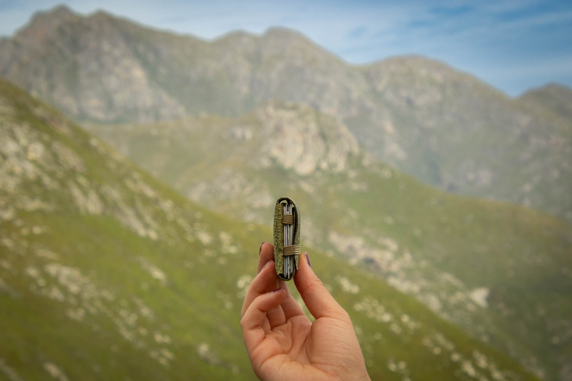 An image capturing the minimalist charm of the wallet against a backdrop of mountains, highlighting its sleek design and impressive capacity for holding numerous cards.